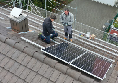 Mathias Grässl und Martin Salzmann von Soleis AG installieren ein Solarpanel auf einem Schrägdach.