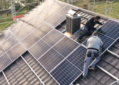 Mathias Grässl und Martin Salzmann von Soleis AG installieren ein Solarpanel auf einem Schrägdach im Sonnenschein.