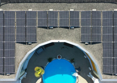 Solarpanels auf Flachdach aus Vogelperspektive, Pool vor dem Haus